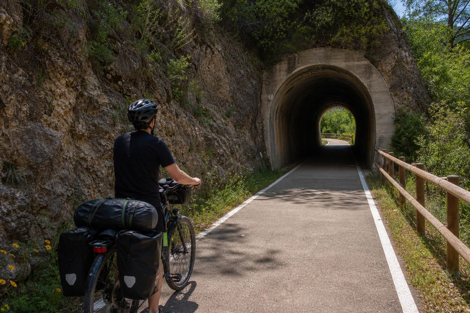 Cyclist approaching a stone railway tunnel on the Baix Ebre greenway